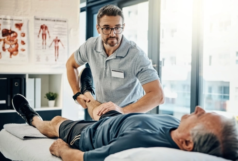fizjoterapeuta masujący pacjentowi kolano